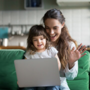 Happy mother and kid girl waving hands making video call