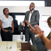 Attractive black businessman being encouraged by diverse multi-ethnic group of coworkers during presentation in office