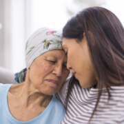 Ethnic elderly woman with cancer embracing her adult daughter